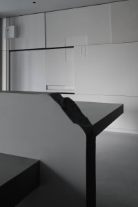 A minimalist bedroom with a concrete floor and walls, featuring a sleek design and modern style.