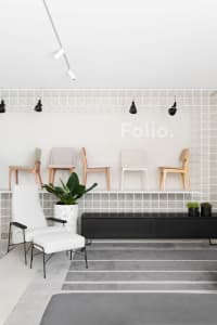 A minimalist retail shop with white-tiled walls and a black storage unit.