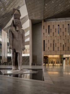 A spacious, modern concrete lobby with a large statue on a pedestal.