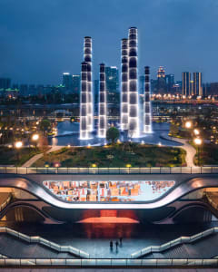 A nighttime cityscape featuring illuminated water fountains in a public space.