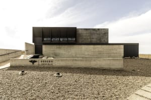 A modern, industrial-style building constructed of concrete with large, dark window panels.