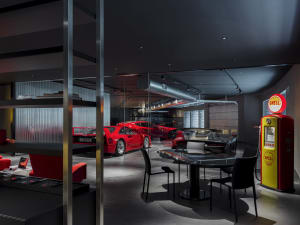 A modern garage exhibit showcasing black and red vehicles, with metallic glass and industrial lighting.