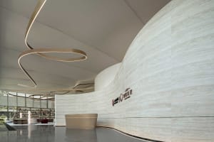 A modern lobby with a marble wall and circular lighting fixture