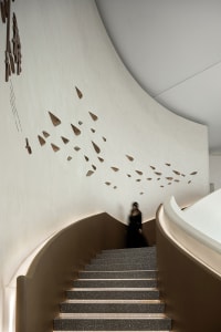 Modern interior featuring a staircase with concrete steps, white textured walls, and abstract artwork resembling dreaming fig
