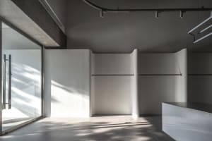 Modern interior design featuring concrete flooring, illuminated lighting fixtures, and minimalist white cabinets against a gr