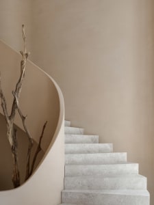 Modern staircase with concrete steps and wall, featuring organic branch as decoration.