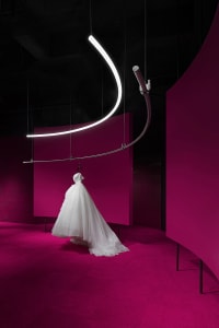 A white dress suspended from a neon light installation.