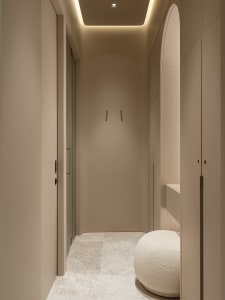 Minimalist corner wardrobe with neutral-toned materials and a cushioned seat.
