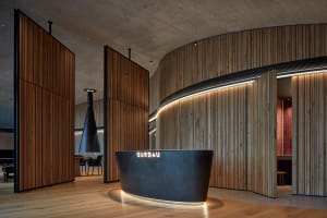Modern lobby interior with wooden, concrete, and metallic reception desk.