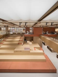 A modern bookstore with a multi-level wood floor plan and open shelves.