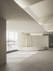 A minimalist office reception area with concrete flooring and seating.