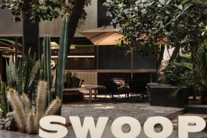 An industrial outdoor patio with concrete flooring, black metal furniture, and plants.