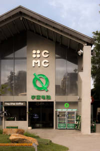 Concrete building exterior with large glass windows and a modern logo