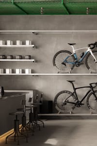 Minimalist interior design featuring a concrete counter, shelves with bicycles, and retail products.