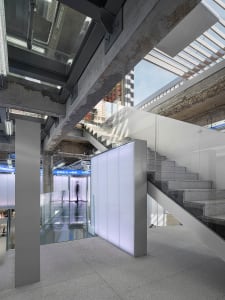 A modern industrial staircase made of concrete with glass railings and a glass partition.