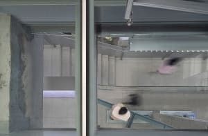 A top-down view of a modern urban concrete and glass walkway with blurred figures indicating movement.