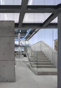 Modern industrial interior with concrete walls, glass railings, and metallic structures