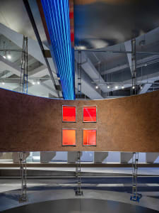 A modern exhibition interior featuring a concrete wall with illuminated panels and metallic structures.