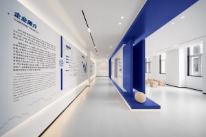 Modern office corridor with white concrete walls and blue accents showcasing company profile information.