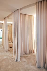 A modern minimalist interior featuring space-partitioning curtains made of fabric.