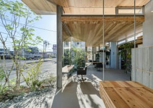 A modern interior space featuring wooden elements, concrete flooring, and large glass walls.
