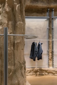 Industrial-style clothing store with concrete walls and black jackets hanging on a circular rail.