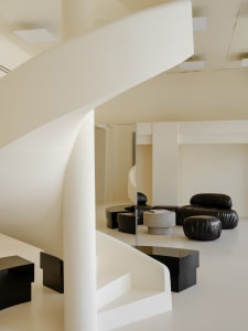 Modern living area with white plaster walls, white furniture, and black accents