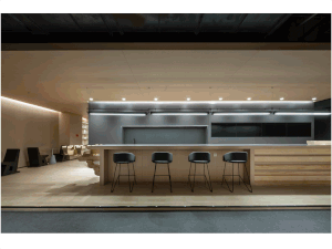 Industrial-style bar counter with four wooden bar stools under a modern lighting fixture.