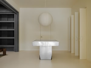 A minimalist bedroom with a white floor, glass doors, and a white pendant lamp.