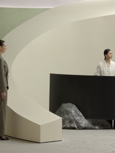 A minimalist interior design featuring a concrete structure and a woman in a white dress.