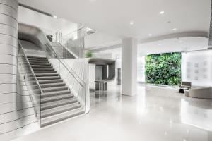 A sleek, minimalist office lobby with modern, white concrete staircase and glass railings.
