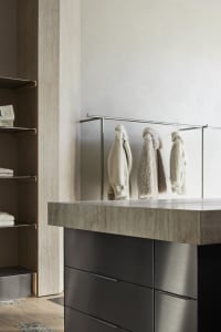 Modern interior design featuring a wardrobe with black concrete material, black metal clothing rail, and luxury closet setup.