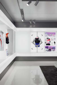 Modern retail space featuring white concrete floors, glass display cases, and minimalist design elements.