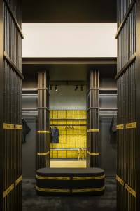 A modern retail store interior featuring concrete-tiled walls and a black seating area.