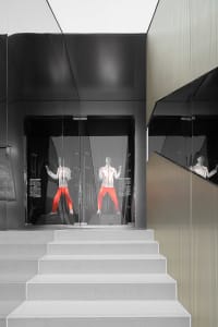 A modern retail storefront with glass walls and white stairs leading up to it.