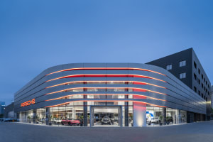 Modern Porsche showroom illuminated at night with red LED lighting and glass facade.