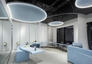 A modern office space with concrete walls, a curved table, and upper lights.