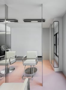 Modern minimalist salon interior with white chairs, glass walls, and pink flooring.