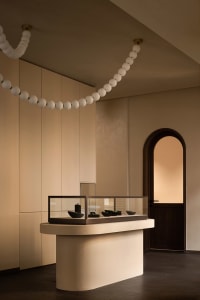 Modern retail shop interior with concrete and glass display case and spherical lighting.