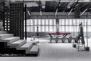 A spacious, modern sports gymnasium with concrete walls and a ping pong table.