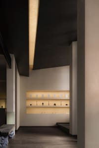 Modern retail shop interior with white concrete display shelves and yellow lighting.