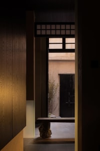 A minimalist interior space featuring wooden walls, stone accents, and metal elements.