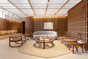 A minimalist modern lounge area with wooden furniture and cloth upholstery, featuring a round coffee table, white sofa, and l
