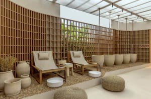 Minimalist spa relaxation room with concrete and wood elements, featuring comfortable seating and plants.