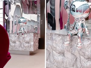 Modern museum installation featuring metallic sculptures and a table draped in aluminum foil.