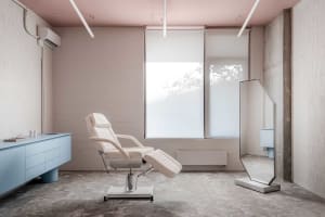 A sleek, minimalist medical office featuring a white leather reclining chair and a large floor-to-ceiling window.