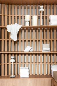 A minimalist shelf made of wood, featuring white towels and candles.