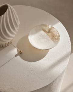 A modern, minimalist ceramic plate with intricate designs placed on a textured white surface.