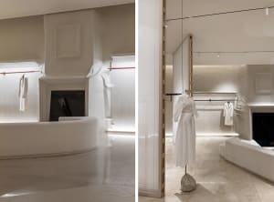 A modern retail store featuring minimalist decor with white marble cladding and minimalist dress forms.