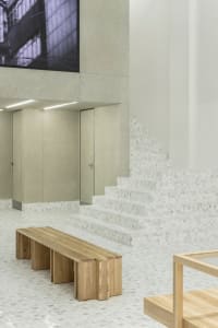Industrial-style interior with concrete walls, marble stairs, and wooden bench and table
